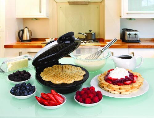 Euro Cuisine waffle maker on a counter with cooked waffle in it and next to it with many toppings in bowls around waffle maker
