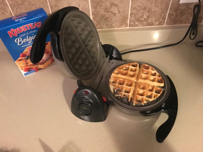 Presto FlipSide Ceramic Belgian Waffle Maker open on the counter with a cooked waffle inside