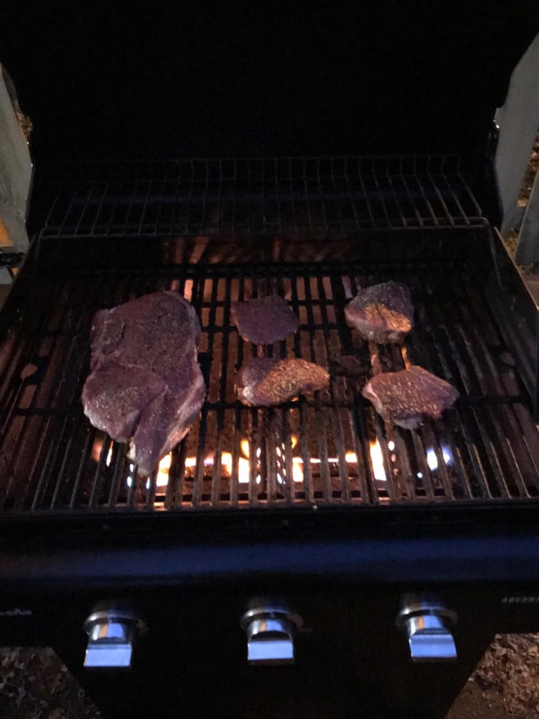 steaks cooking on a grill